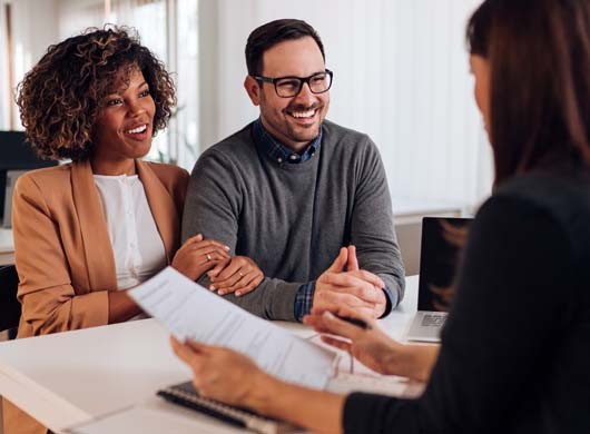 Couple consulting with a female financial manager at the bank about real estate loan