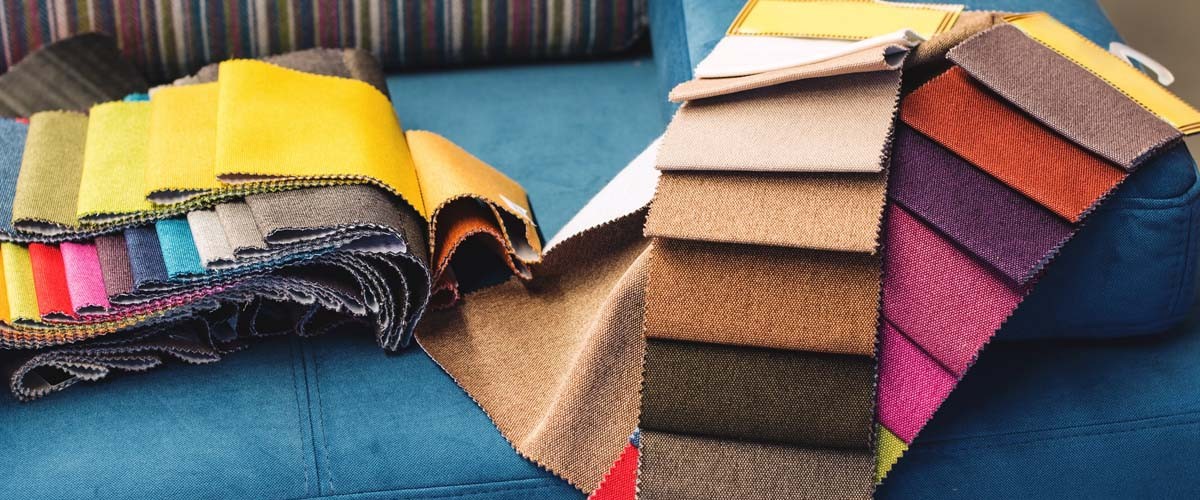 Upholstery fabric samples in different colours on a blue sofa in a furniture store.