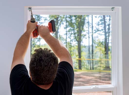 This is professional technician installing blinds on windows of newly constructed home by screwing the fasteners in